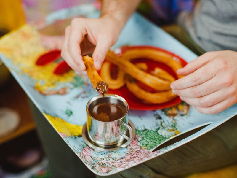 Hand dipping churros into chocolate